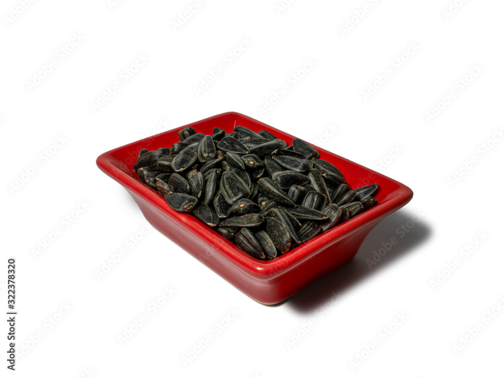 Sunflower seeds in a red rectangular saucer isolated on white background. Close-up Sunflower seeds in a red rectangular saucer isolated on white background. Close-up