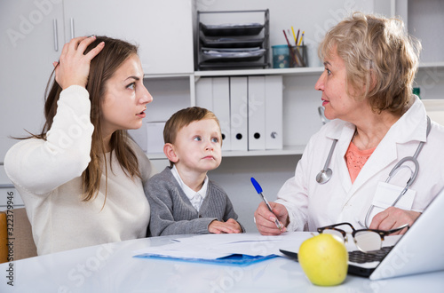Puzzled woman is listening woman doctor about diagnosis her son