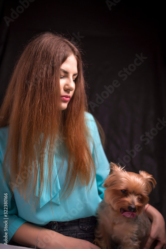 Portrait of a girl with a dog against a dark background.