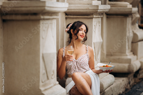 pretty woman with candid smile laughing sitting at summer cafe, dressed in white printed dress, fashionable street style