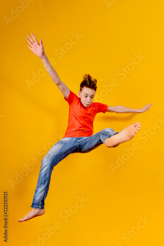 Funny and crazy boy jumps up on a yellow background, wide angle photo.