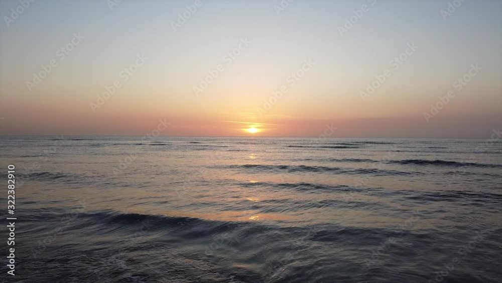 Drone dolly shot heading towards the sunset over the beach, calm ocean waves crashing on the sandy shore. Filmed in the winter but could almost be mistaken for a beautiful summer sunset at dusk. Drone dolly shot heading towards the sunset over the beach, calm ocean waves crashing on the sandy shore. Filmed in the winter but could almost be mistaken for a beautiful summer sunset at dusk.