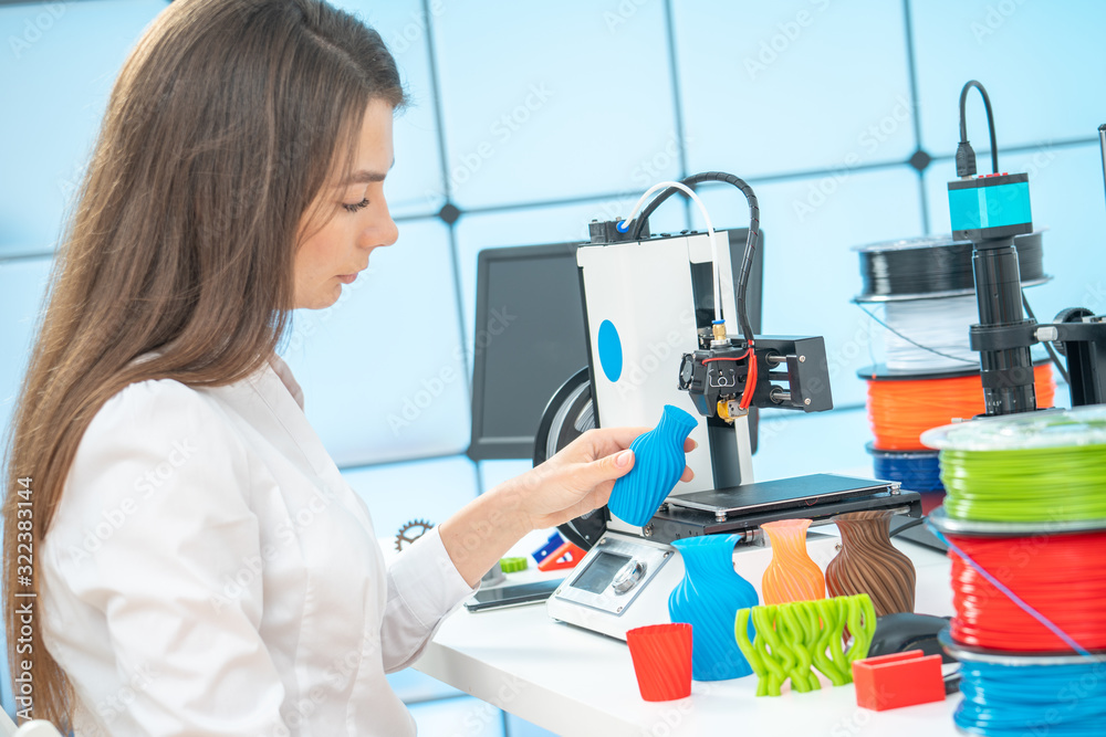 Young female designer works with a 3D printer in a design studio. Young female designer works with a 3D printer in a design studio.