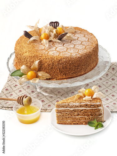 food photography of honey cake, whole and piece closeup, decorated with chocolate and physalis on a white background isolated