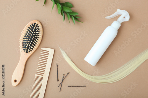 A lock of blonde hair  hair care products and a comb on a colored background top view.