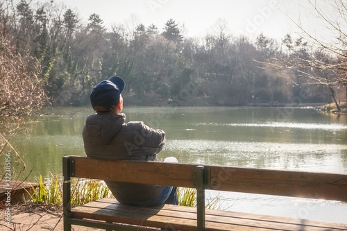 Photography man with a cap sitting and relaxing on a bench near lake in the park Kurpark Ob