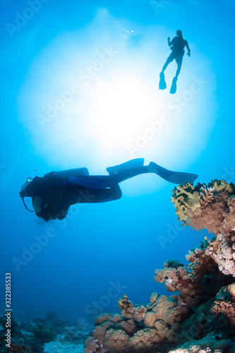 Underwater image of Scuba Divers silhouetted against sun
