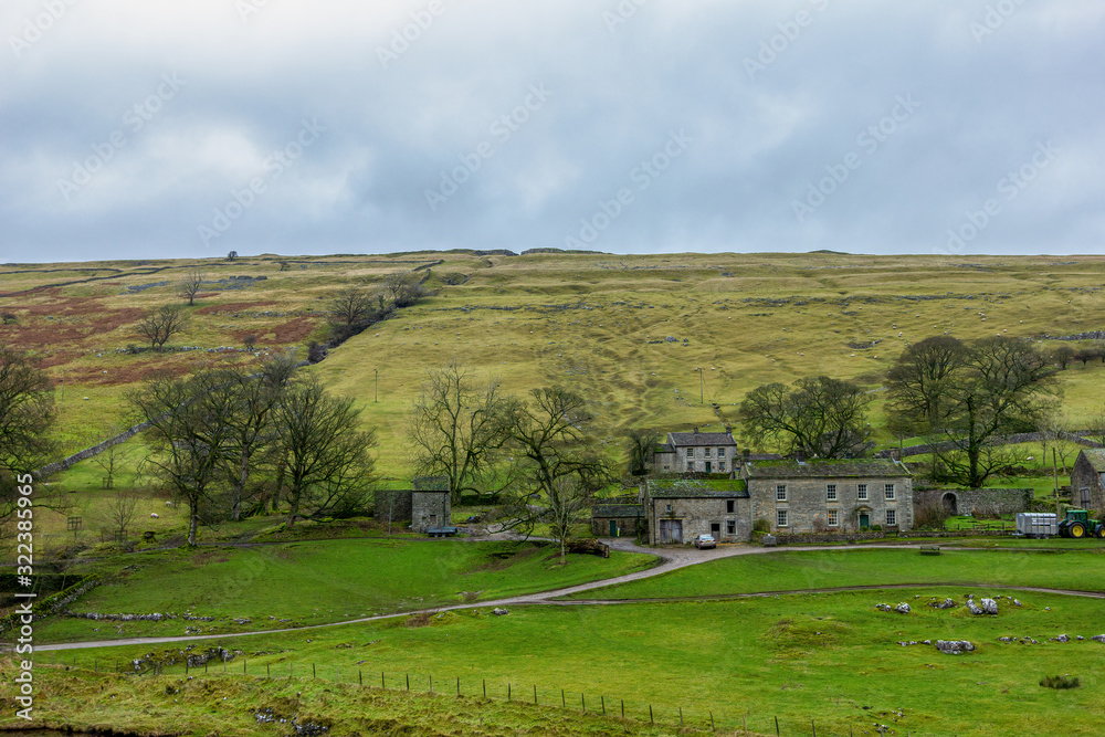 A scenic view of a mountain farm building with grassy slope under a grey sky
