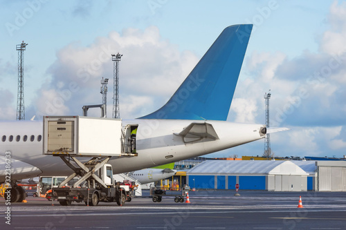Airplane tail view- service before flights, service machine for loading.