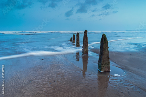 Weathered beach groynes on Westward Ho beach facing the on rushing waves from Bideford Bay on the North Devon coast of England.