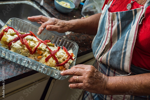 older woman preparing russian salad with mayonnaise potatoes bell peppers and olives