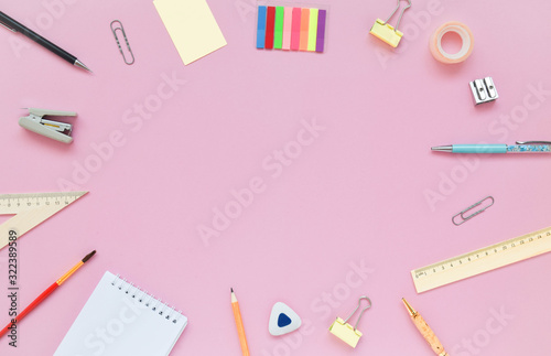Stationary, back to school,creativity and education concept. Notebook, pen, pencil, eraser, ruler, paper clips, stapler, brush on pink background, flat lay. Top view