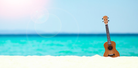 ukulele on the sand by the sea in summer
