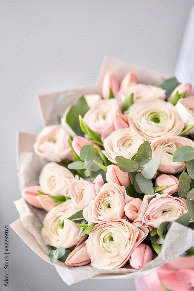 Obraz premium Bunch pale pink tulips and ranunculus flowers with green eucalyptus. The work of the florist at a flower shop.
