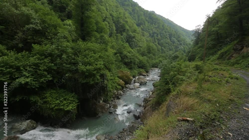 Cinematic video of a drone flying over a river stream in the mountains. Aerial video of the drone moving above the river. Top view of a bus moving on riverside road. Cinematic video of a drone flying over a river stream in the mountains. Aerial video of the drone moving above the river. Top view of a bus moving on riverside road.