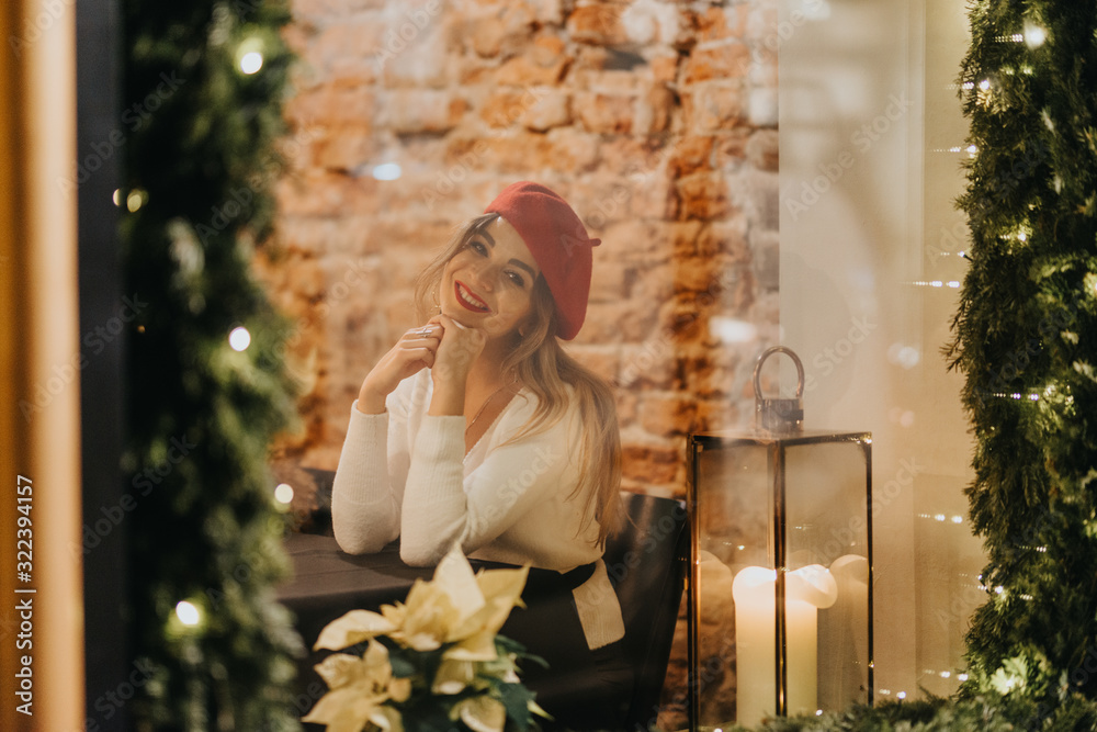 Fototapeta premium A beautiful young woman seen through the site of a festively decorated restaurant.