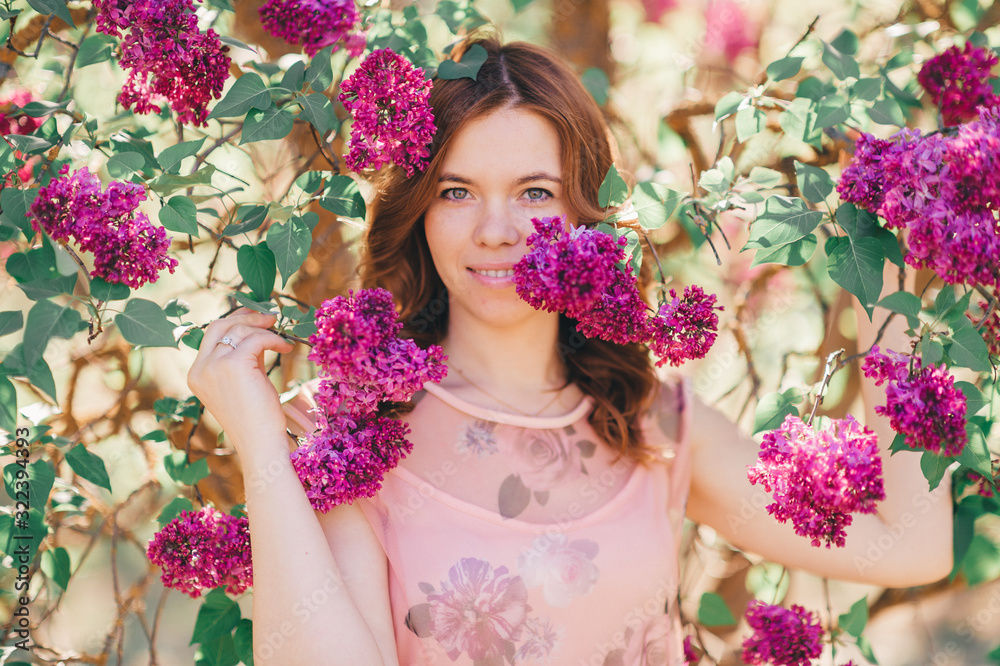 Handsome brown hair girl in light dress near the lilac tree smiles Handsome brown hair girl in light dress near the lilac tree smiles