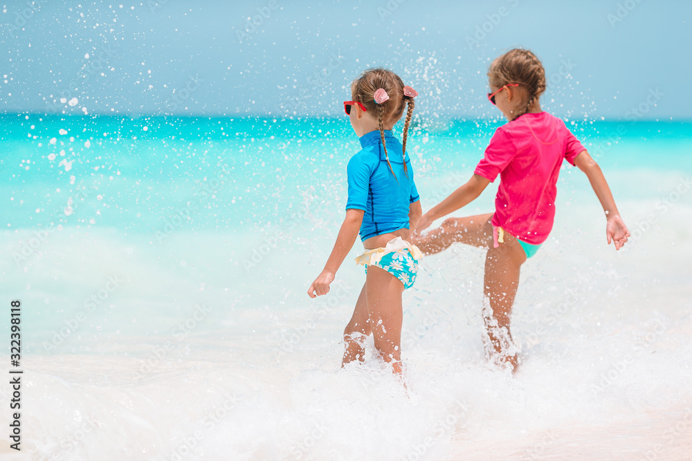 Adorable little girls have fun on white beach during vacation Adorable little girls have fun on white beach during vacation