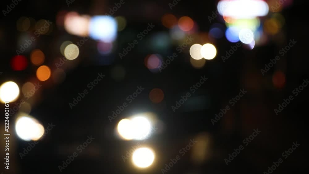 Silhouettes of people sitting down in a parked car. Colorful defocused Lights of night road. Defocus headlights of moving cars urban traffic. Abstract bright blured colored bokeh. Silhouettes of people sitting down in a parked car. Colorful defocused Lights of night road. Defocus headlights of moving cars urban traffic. Abstract bright blured colored bokeh.