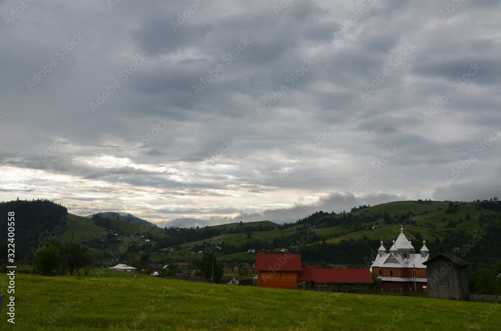 Modest houses of the Carpathian village in the valleys near the green mountains . For your design