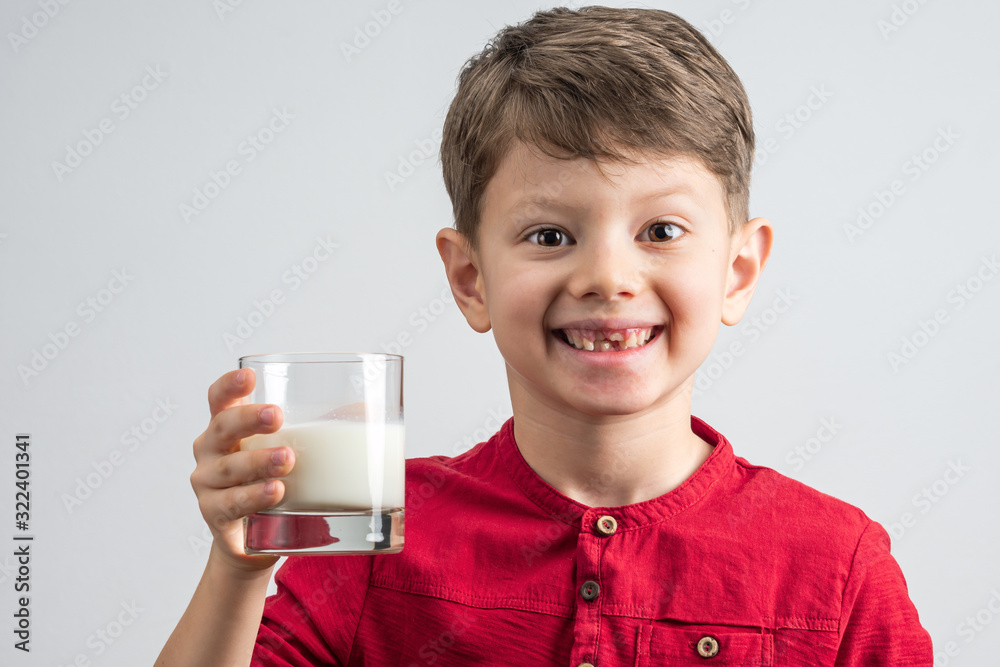 Toothles smiling boy holds a glass of milk in his hand Toothles smiling boy holds a glass of milk in his hand