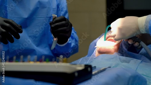 The dentist surgeon performs an implant placement operation