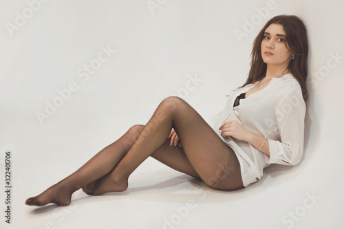 A woman dressed in a white felling and black tights on a white background.