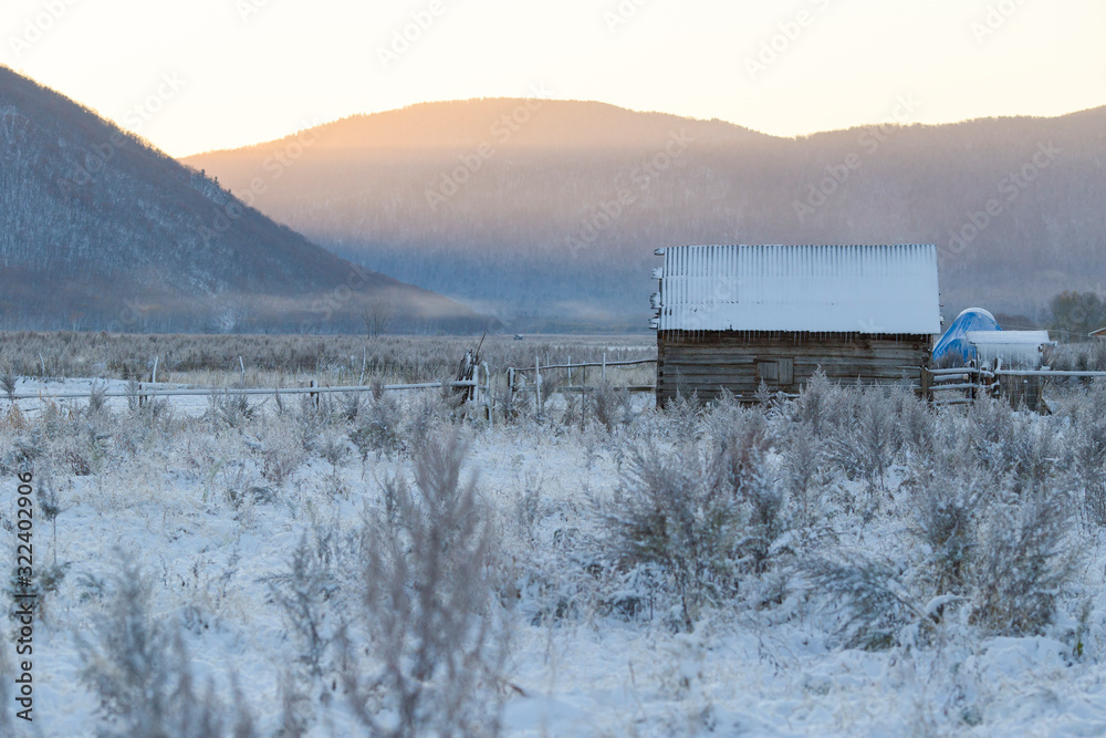 The village of Latin American Old Believers who returned to Russia in the Primorsky Territory. Wooden houses of Old Believers during a snowfall on a background of beautiful fields and mountains. The village of Latin American Old Believers who returned to Russia in the Primorsky Territory. Wooden houses of Old Believers during a snowfall on a background of beautiful fields and mountains.