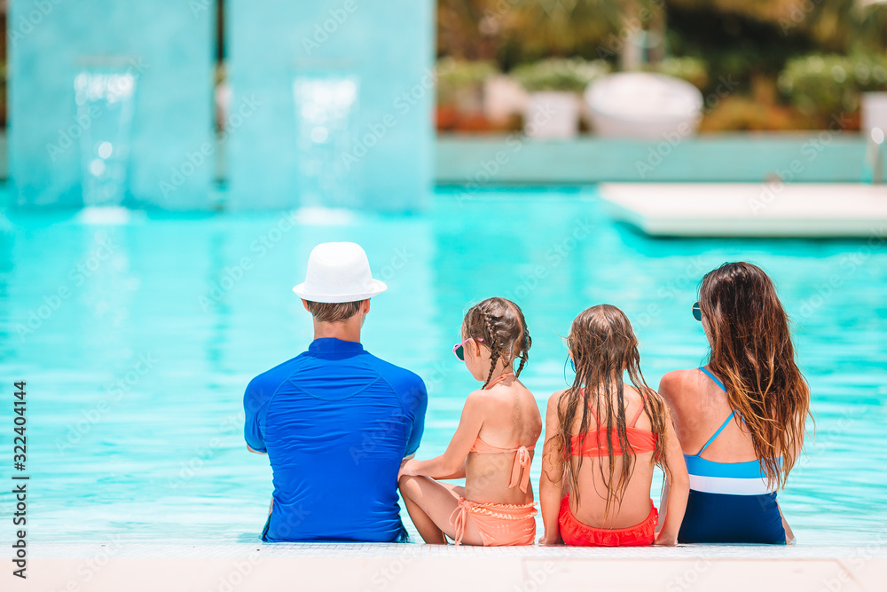 Fototapeta premium Happy family of four in outdoors swimming pool