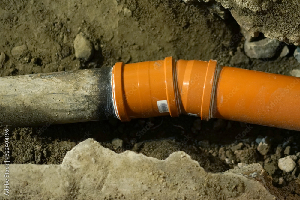 Replacing old cast iron sewer pipe with new pvc pipe. Stock Photo