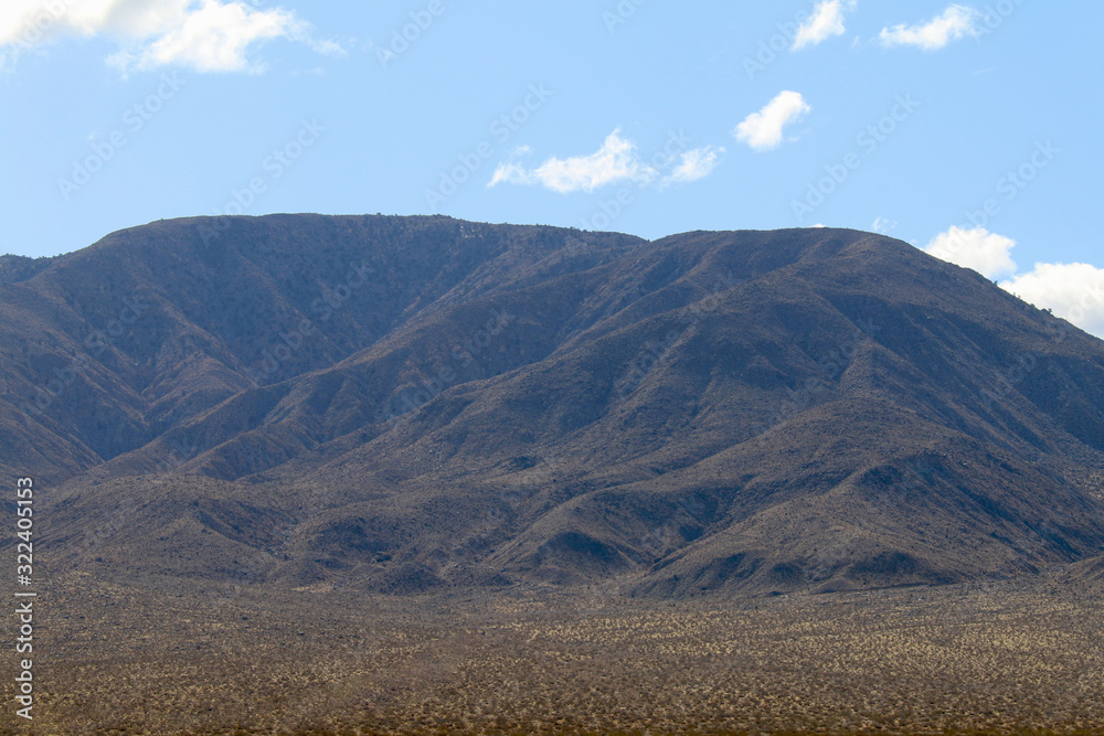 a distant desert mountain range on a cloudy blue sky