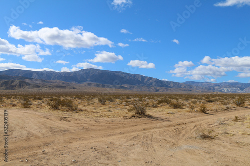 a dry desert road with mountains and blue sky