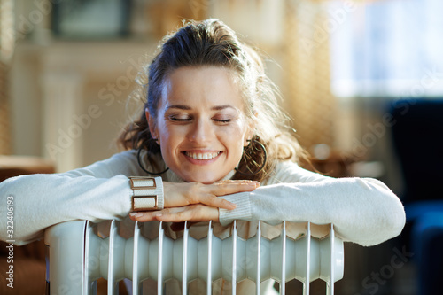 woman at modern home in sunny winter day near warm radiator