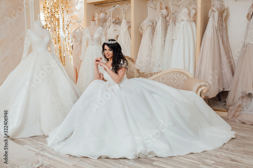 Young happy bride looking for beautiful wedding dress, future bride came in designers salon, lovely woman dream about wedding. Beautiful bride choosing wedding dress in a wedding salon