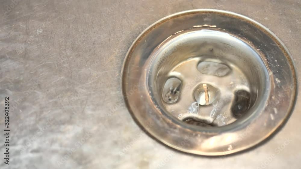 Stainless steel kitchen sink with running water. The faucet is turned right up. a strong water jet flows into the basin. small bubbles and swirls are seen. the water flows through the open drain. Stainless steel kitchen sink with running water. The faucet is turned right up. a strong water jet flows into the basin. small bubbles and swirls are seen. the water flows through the open drain.