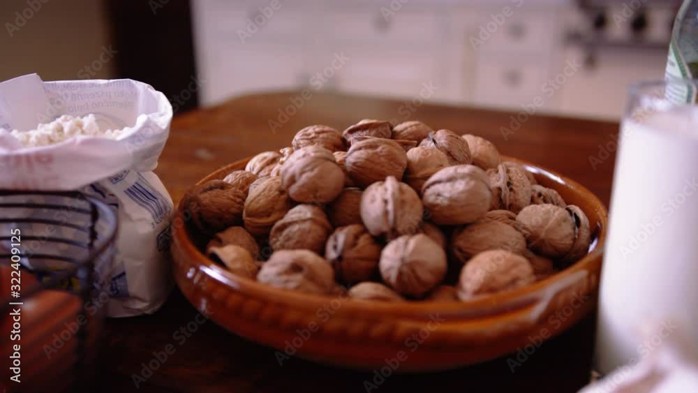 Beautiful panning shot of ingredients including parmesan cheese, walnuts in their shell, cream, garlic, nutmeg. Ingredients used to make walnut ravioli pasta. Beautiful panning shot of ingredients including parmesan cheese, walnuts in their shell, cream, garlic, nutmeg. Ingredients used to make walnut ravioli pasta.