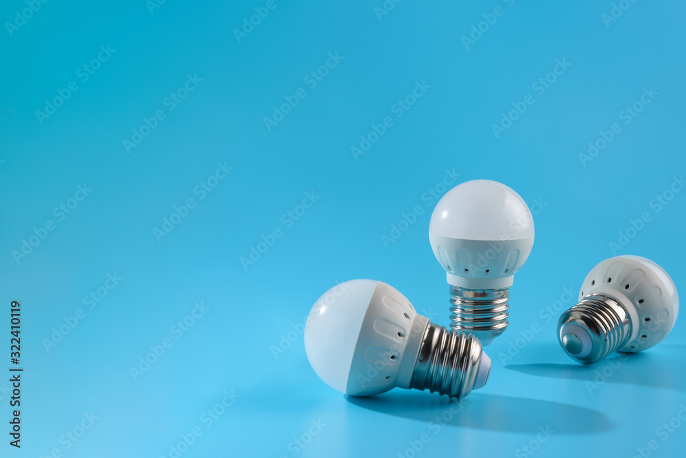 Three small white led energy saving led light bulbs on a blue background. Three small white led energy saving led light bulbs on a blue background.
