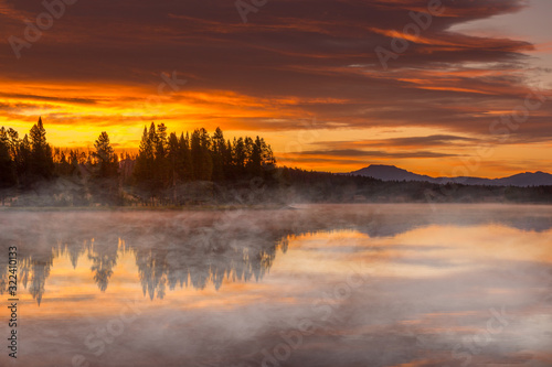 Burning sky, sunrise and morning fog at the lake. Yellowstone National Park