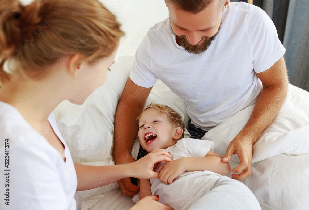 happy family mother, father and child son laughing, playing, fights pillows and jumping in bed at home. happy family mother, father and child son laughing, playing, fights pillows and jumping in bed at home.