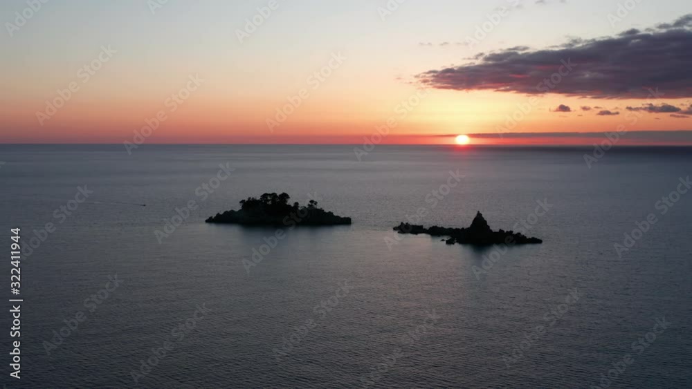 Two islets (Katic and Sveta Nedjelja - Saint Sunday) off Petrovac Montengro, on the coast of the Adriatic sea. Silhouettes against colorful sunset sky with sun low on the horizon. Aerial footage. Two islets (Katic and Sveta Nedjelja - Saint Sunday) off Petrovac Montengro, on the coast of the Adriatic sea. Silhouettes against colorful sunset sky with sun low on the horizon. Aerial footage.