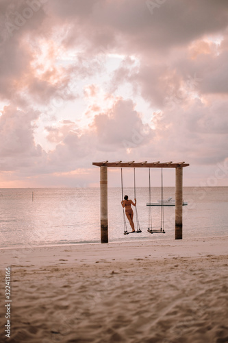 Woman on a swing at the sea at sunset, Maguhdhuvaa Island, Gaafu Dhaalu Atoll, Maldives photo