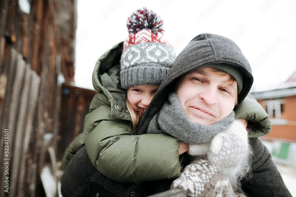Portrait of father carrying daughter piggyback outdoors in winter Portrait of father carrying daughter piggyback outdoors in winter