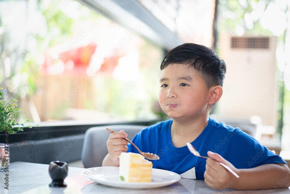 Asian boy eating cake in bakery shop or cafe. Asian boy eating cake in bakery shop or cafe.