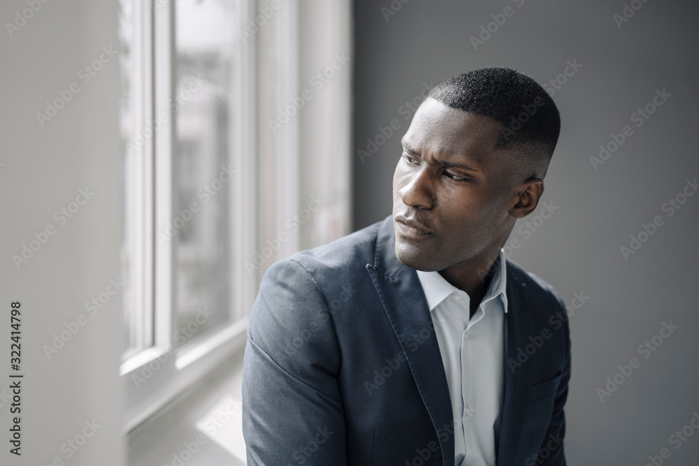 Portrait of serious young businessman looking out of window Portrait of serious young businessman looking out of window