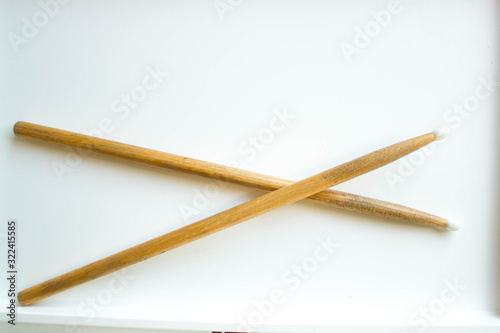 Two crossed wooden drumsticks on a white background.