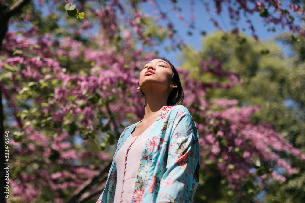 Beautiful young woman with blooming cherry tree in a public garden in spring Beautiful young woman with blooming cherry tree in a public garden in spring