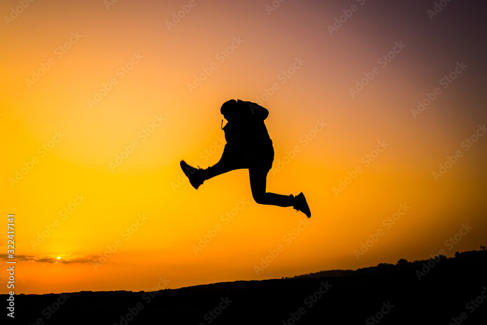 Silhouette man on sky background. Sport and active life,The Traveler jumping on top of the Mountain on sunset cloud sky.Victory concept.