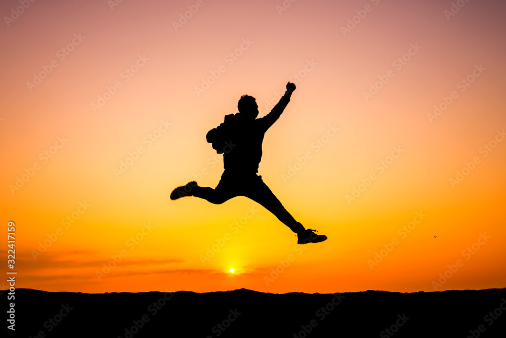 Silhouette man on sky background. Sport and active life,The Traveler jumping on top of the Mountain on sunset cloud sky.Victory concept.