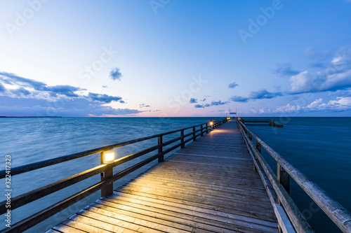 Germany,?Mecklenburg-Western Pomerania, Prerow, Illuminated pier at dusk with clear line of horizon over Baltic Sea in background photo