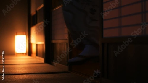 Slow motion of traditional Japanese house ryokan with tatami mat floor, shoji sliding paper doors and woman in kimono and geta shoes tabi socks walking in corridor hall room